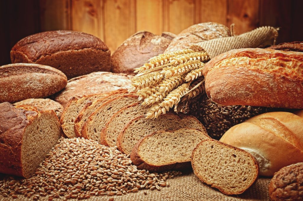 Viele verschiedene Brote und Getreide liegen schön angerichtet auf einem ausgebreiteten Leinensack.