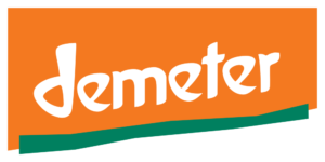 Oranger Hintergrund, eine dunkelgrüne schräge Linie, auf der in weißer Schrift "Demeter" steht
