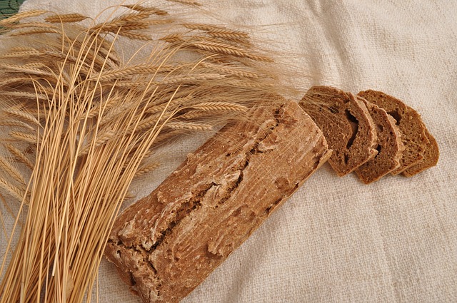 Auf einem Leinentuch liegen einige Ähren von Urgetreide und ein aufgeschnittenes Brot.
