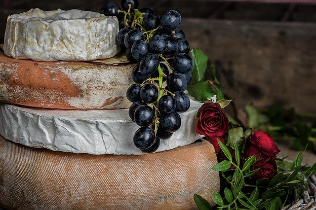 Eine Torte aus mehreren Käselaibern, auf der Weintrauben und Blüten dekoriert sind.