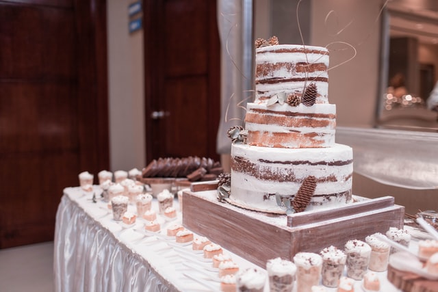 Ein Naked Cake steht als Hochzeitskuchen auf dem Buffet, umringt von kleinen dazu passenden Cupcakes