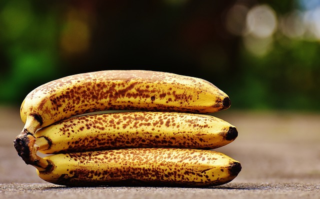 Drei Bananen mit braun gefleckten Schalen liegen im Freien